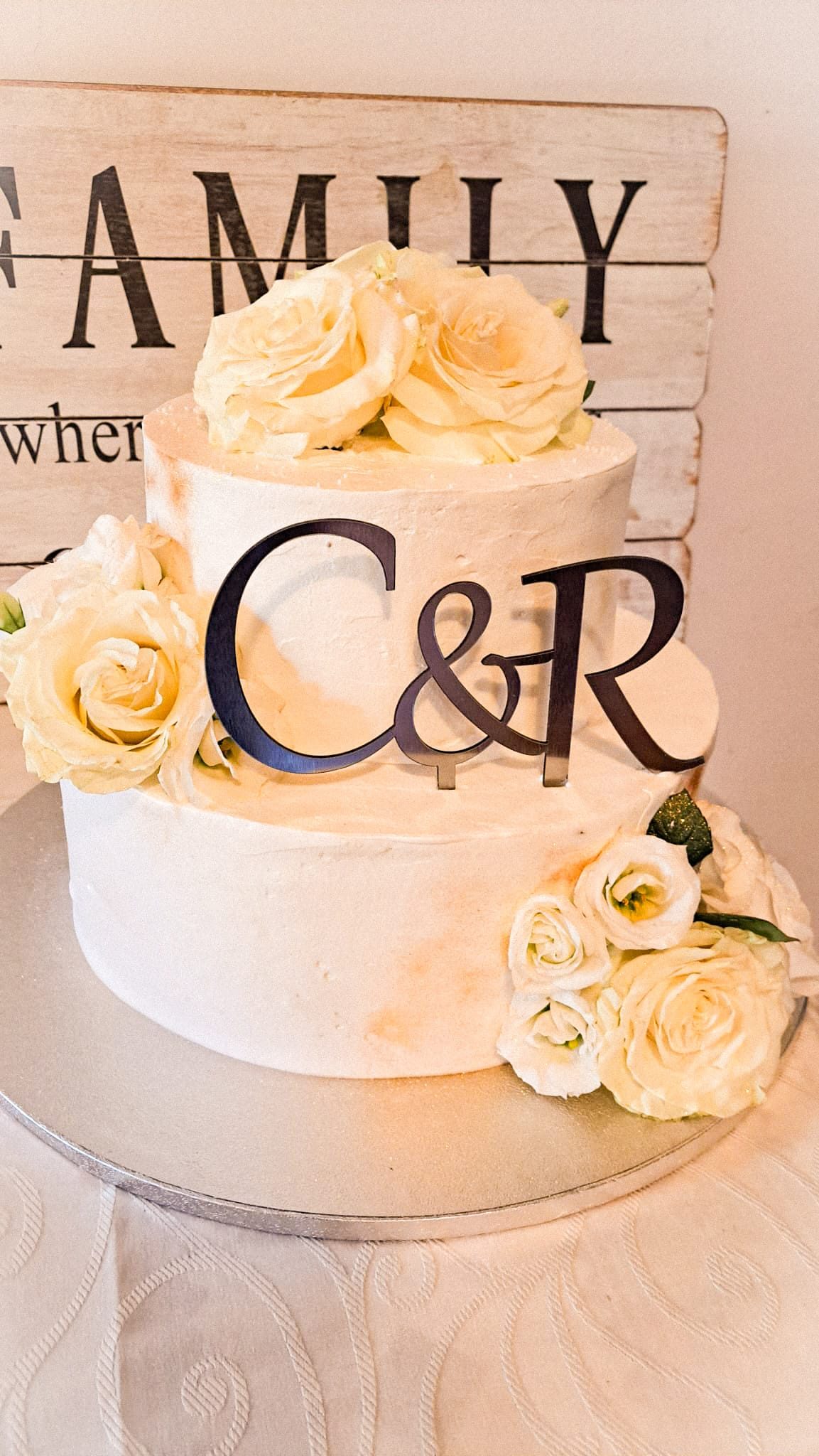 Tort de nuntă cu două etaje, finisaj alb și trandafiri crem, cu monogramă, realizat de Cofetăria Giumbo
