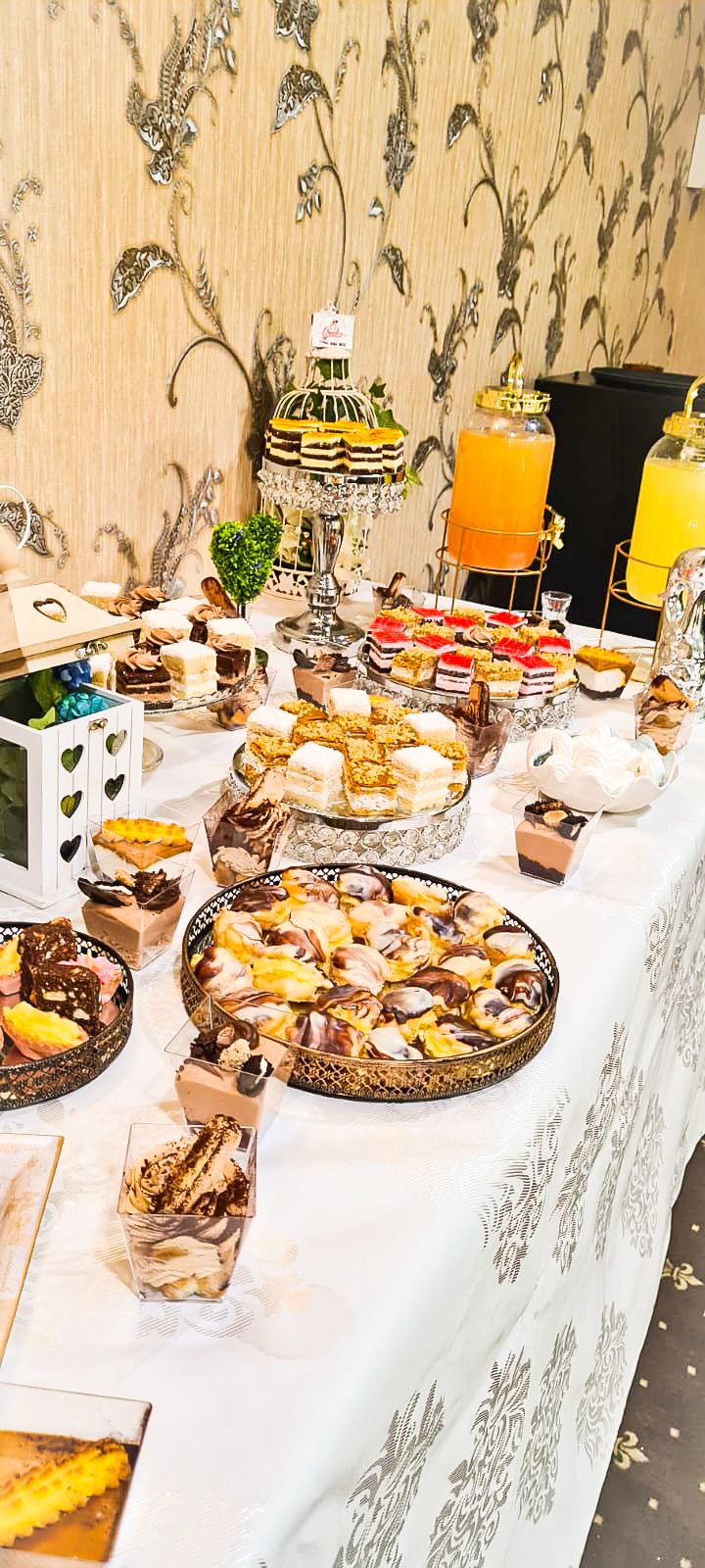 Masă dulce de eveniment pregătită de Cofetăria Giumbo, cu prăjituri asortate pe platouri și suporturi etajate