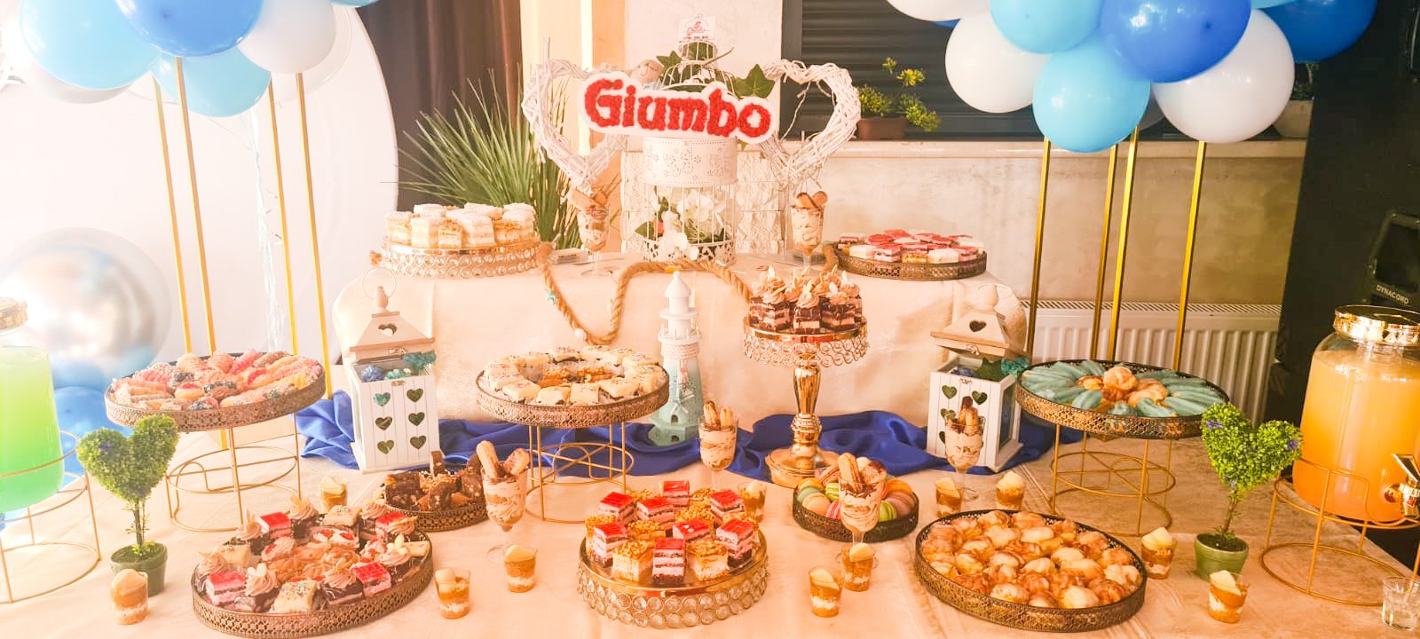 Masă dulce de eveniment pregătită de Cofetăria Giumbo, cu decor de baloane în nuanțe de albastru și alb
