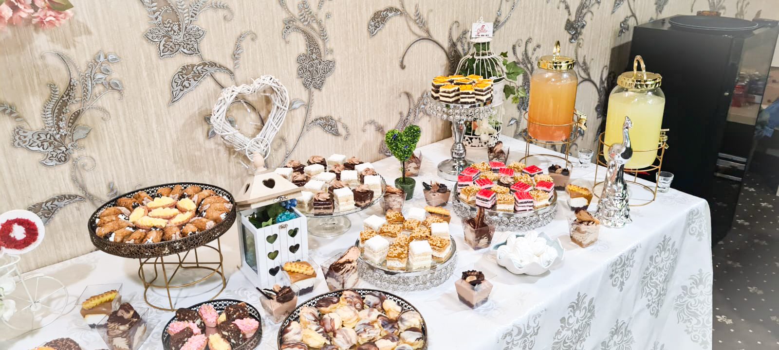 Masă dulce de eveniment pregătită de Cofetăria Giumbo, cu suporturi etajate, prăjituri și limonade